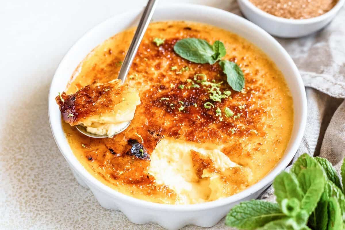 pumpkin crème brûlée with a caramelized sugar topping, showing a spoonful of creamy custard beneath the crisp brûléed crust