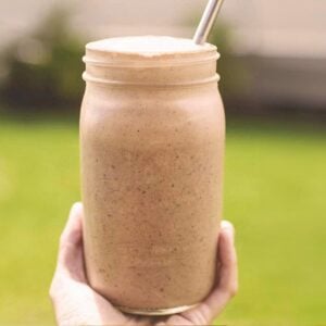 hand holding a glass jar filled with chocolate peanut butter smoothie