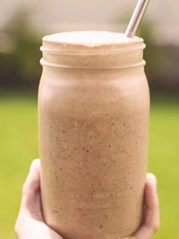 hand holding a glass jar filled with chocolate peanut butter smoothie