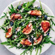top view of arugula fig salad arranged on a white dish