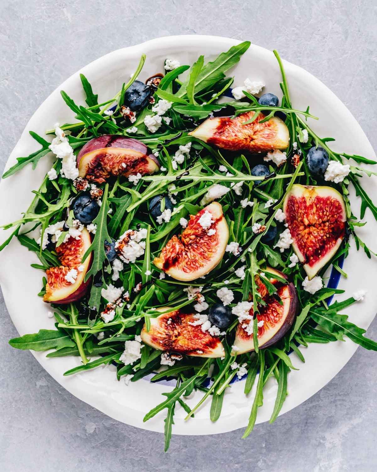 top view of arugula fig salad arranged on a white dish