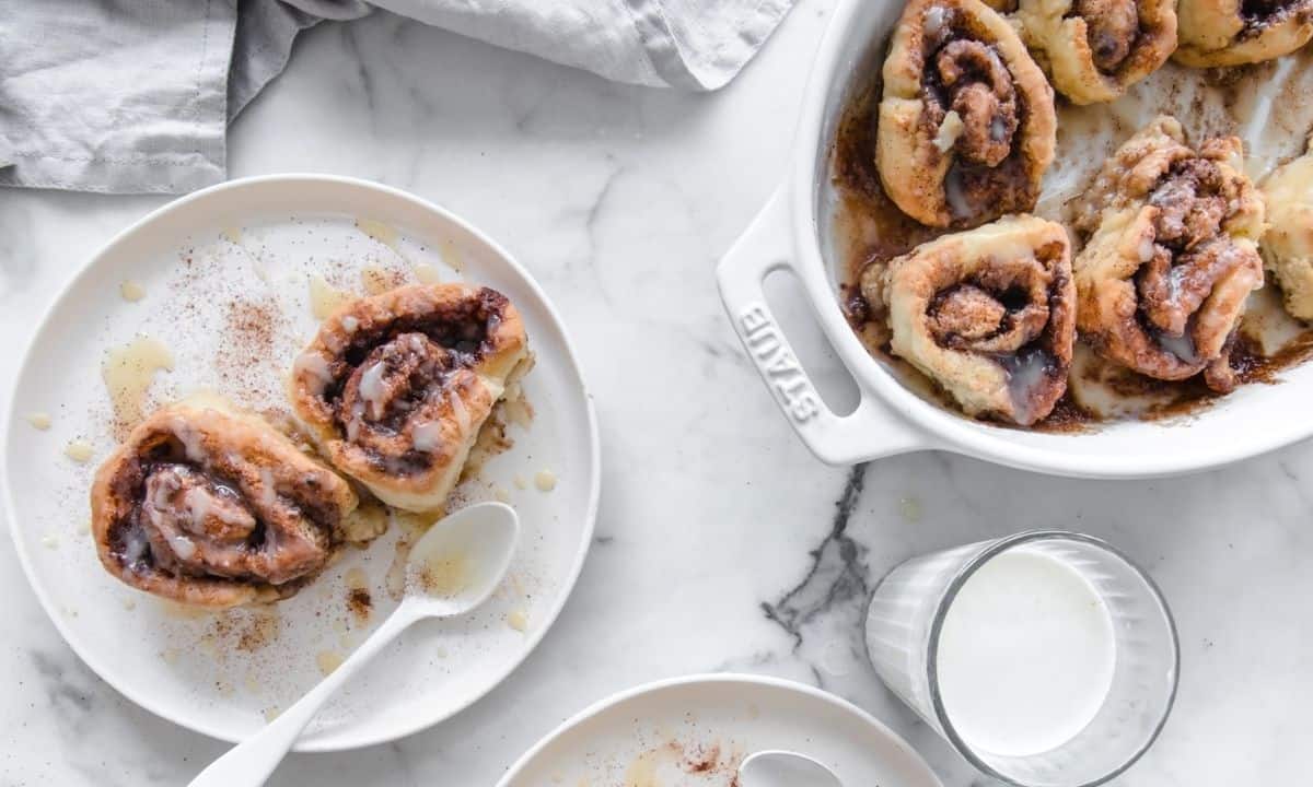 two whole wheat cinnamon rolls in a dish and more in a baking dish