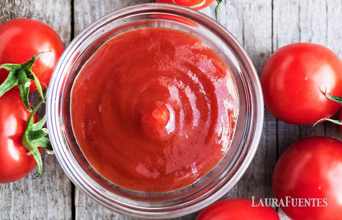 overhead view of small glass dish of homemade ketchup with tomatoes around it