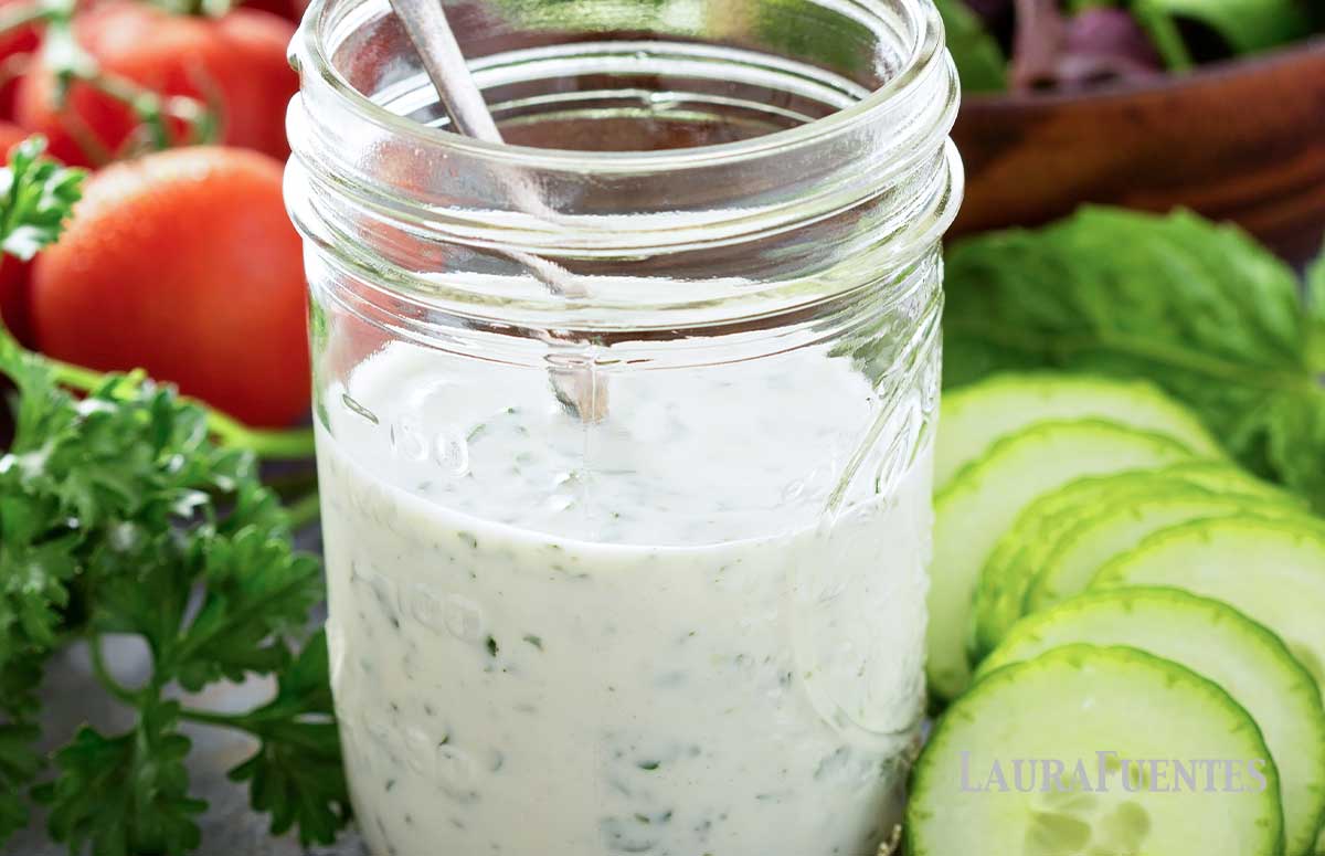 small jar of homemade ranch dressing on a table with sliced vegetables
