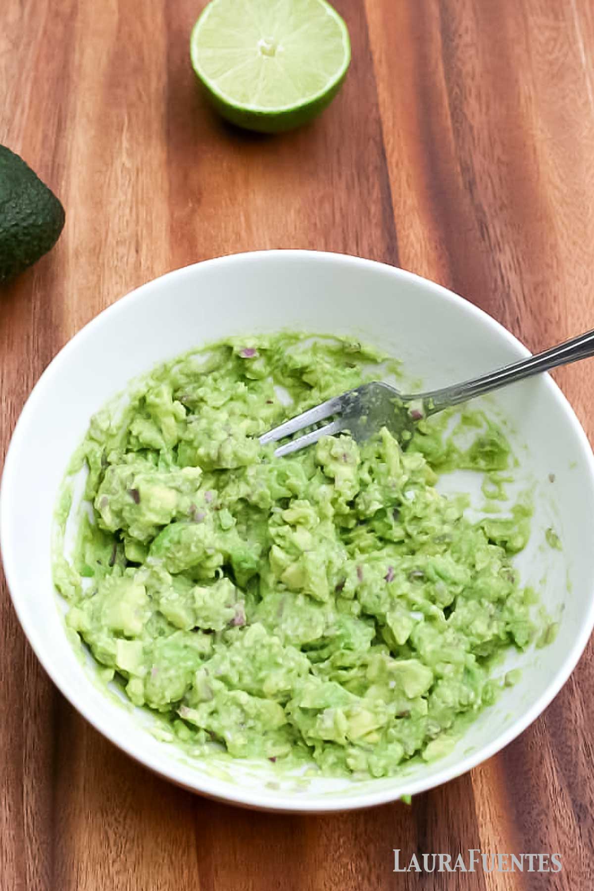 overhead view of guacamole in a white plate with a fork