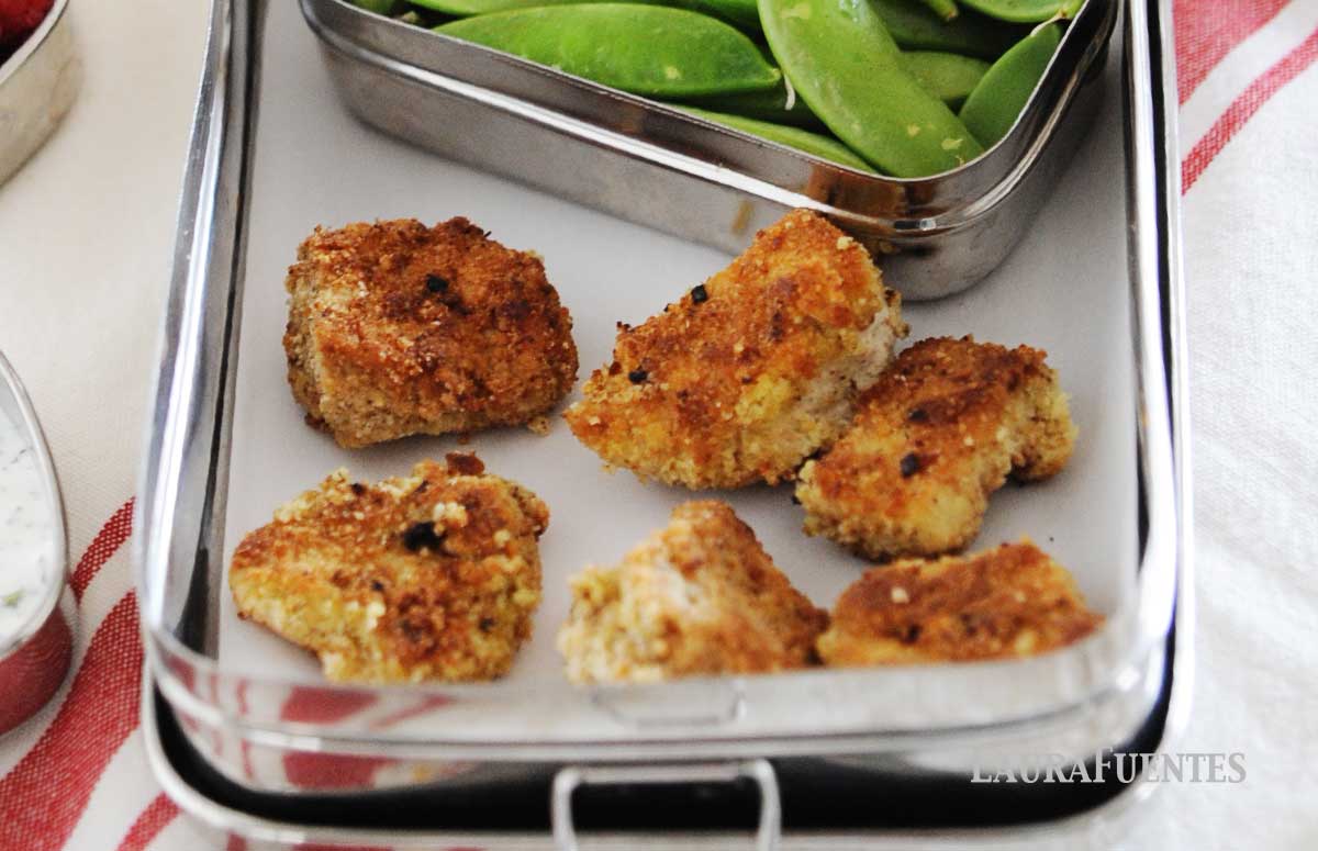 lunchbox with six chicken nuggets and veggies on the side.