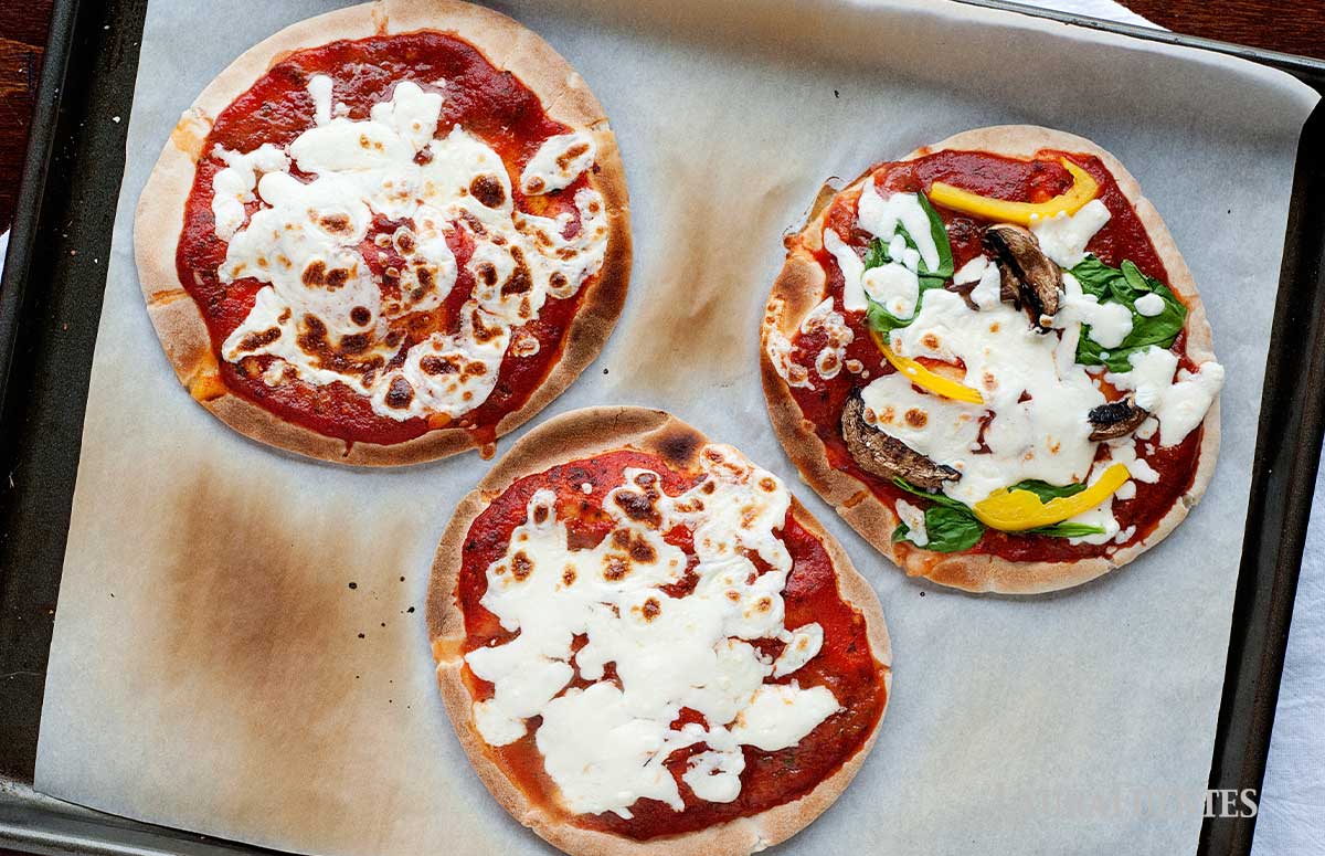 three pizza pitas on a baking sheet