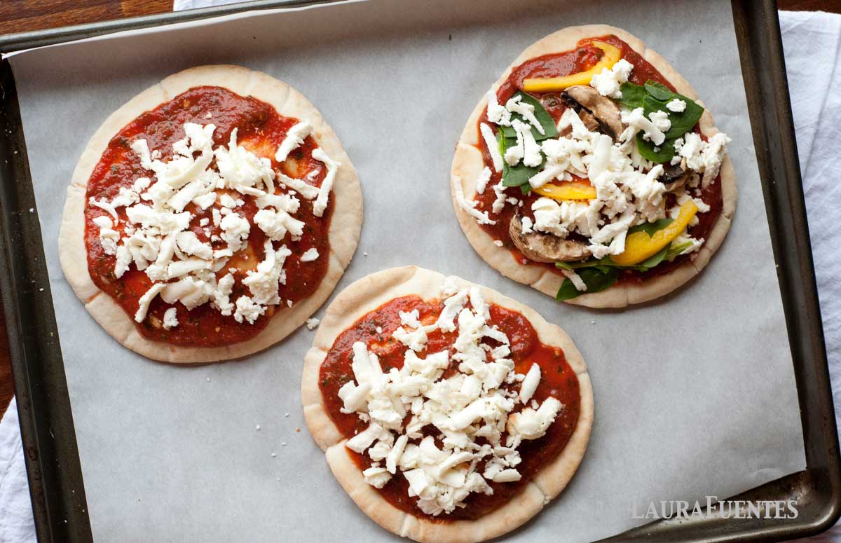 three pizza pitas on a baking sheet before baking