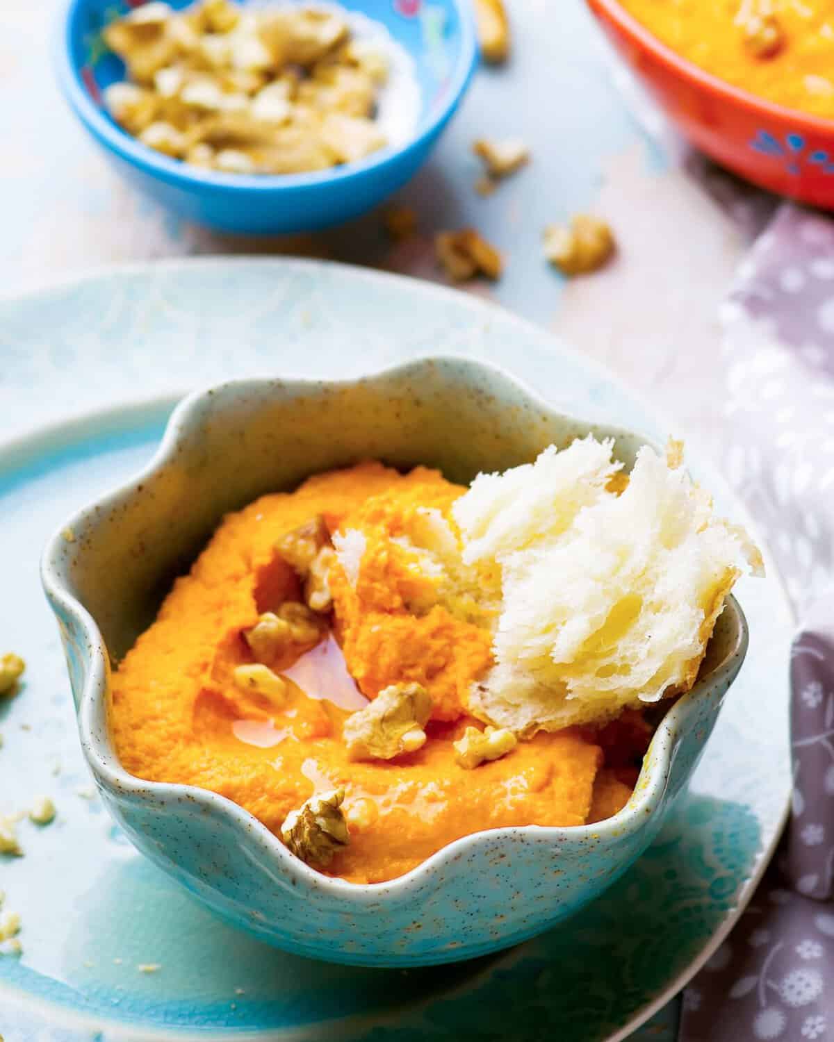a bowl of sweet potato hummus with some bread on the side
