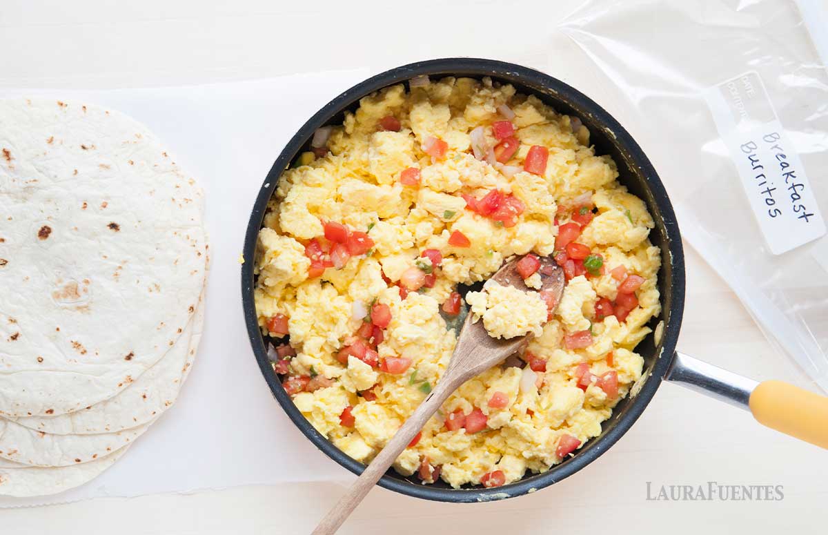 breakfast burritos reaoverside view of breakfast tortilla stuffing in a pan and tortilla wraps on the sidedy to be wrapped