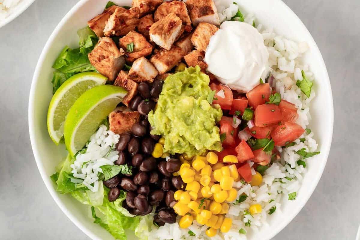 overhead view of a chipotle chicken burrito bowl with corn, beans, guacamole, sour cream and cilantro lime rice and lettuce