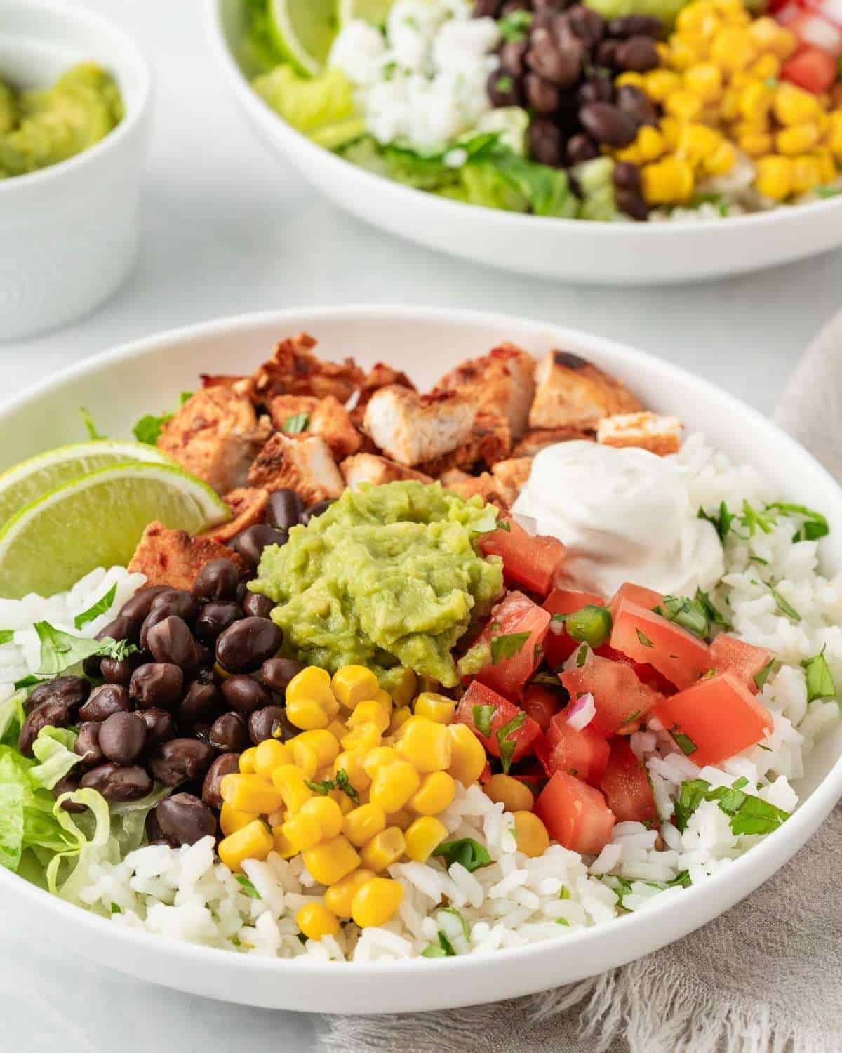a chipotle chicken burrito bowl with corn, beans, guacamole, sour cream and cilantro lime rice and lettuce