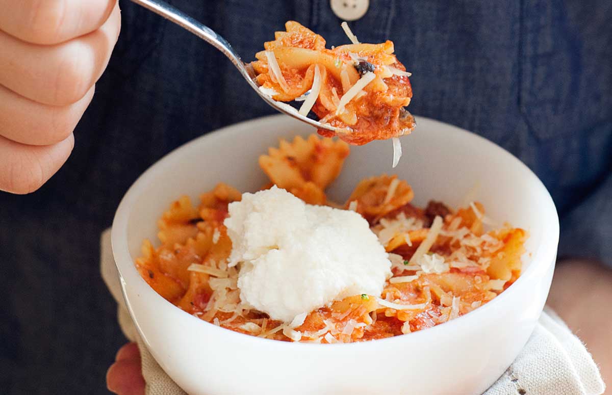 bowtie pasta in a bowl with tomato sauce and a dollop of ricotta cheese, serving of skillet lasagna