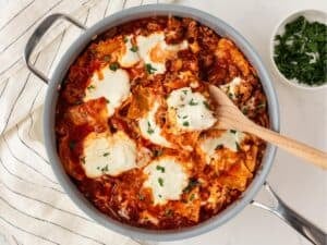 overhead view of a skillet with lasagna made with lasagna noodles, tomato sauce, meat, and cheeses