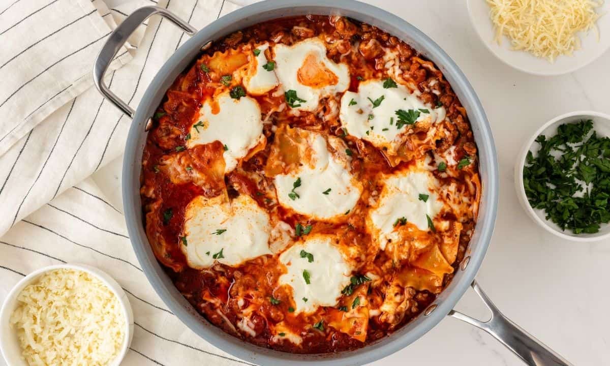 overhead view of a skillet with lasagna made with lasagna noodles, tomato sauce, meat, and cheeses