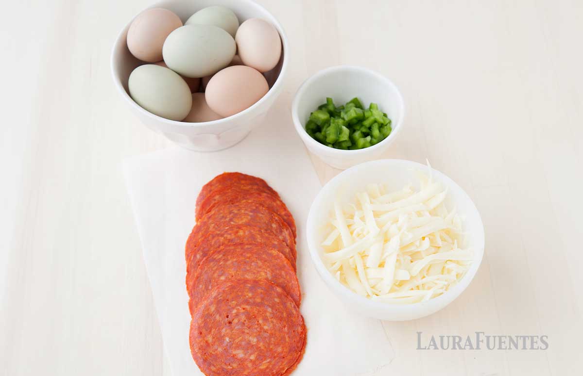 ingredients of mini pizza quiches: eggs, chopped pizza toppings, shredded cheese