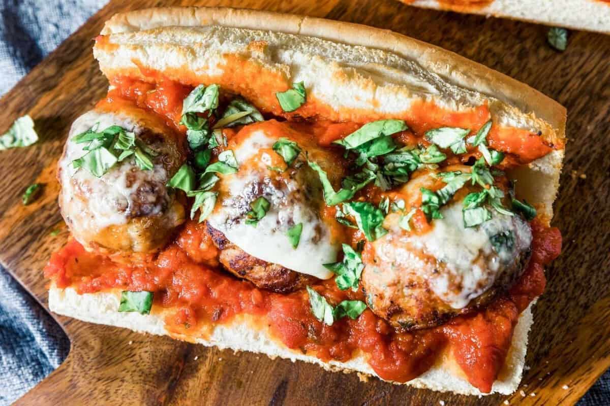 three large meatballs on a sub with red sauce and cheese