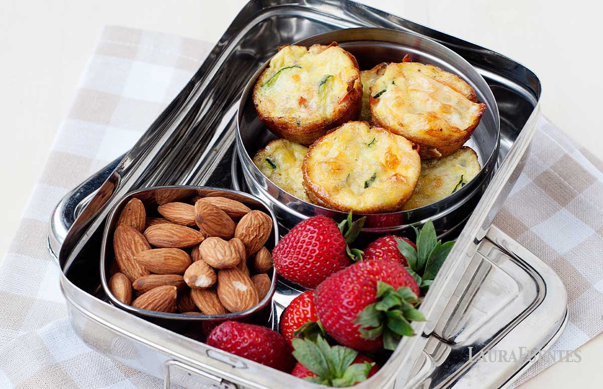 silver lunchbox with bowl of almonds, strawberries and small mini quiches