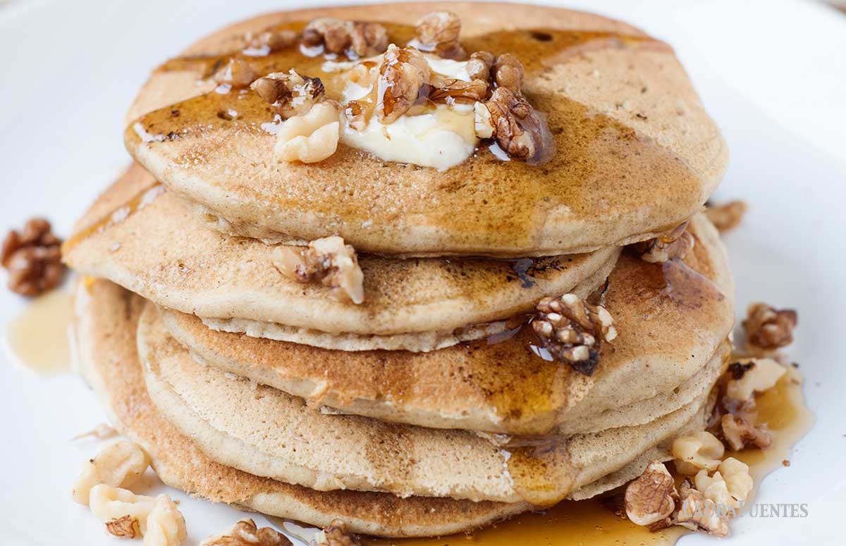 stack of banana bread pancakes topped with nuts and syrup