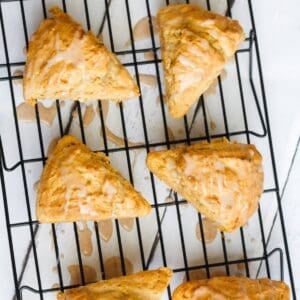 four pumpkin scones with glaze on a cooling rack