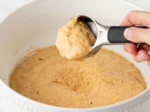 close up of pumpkin pancake batter in a scoop to show texture