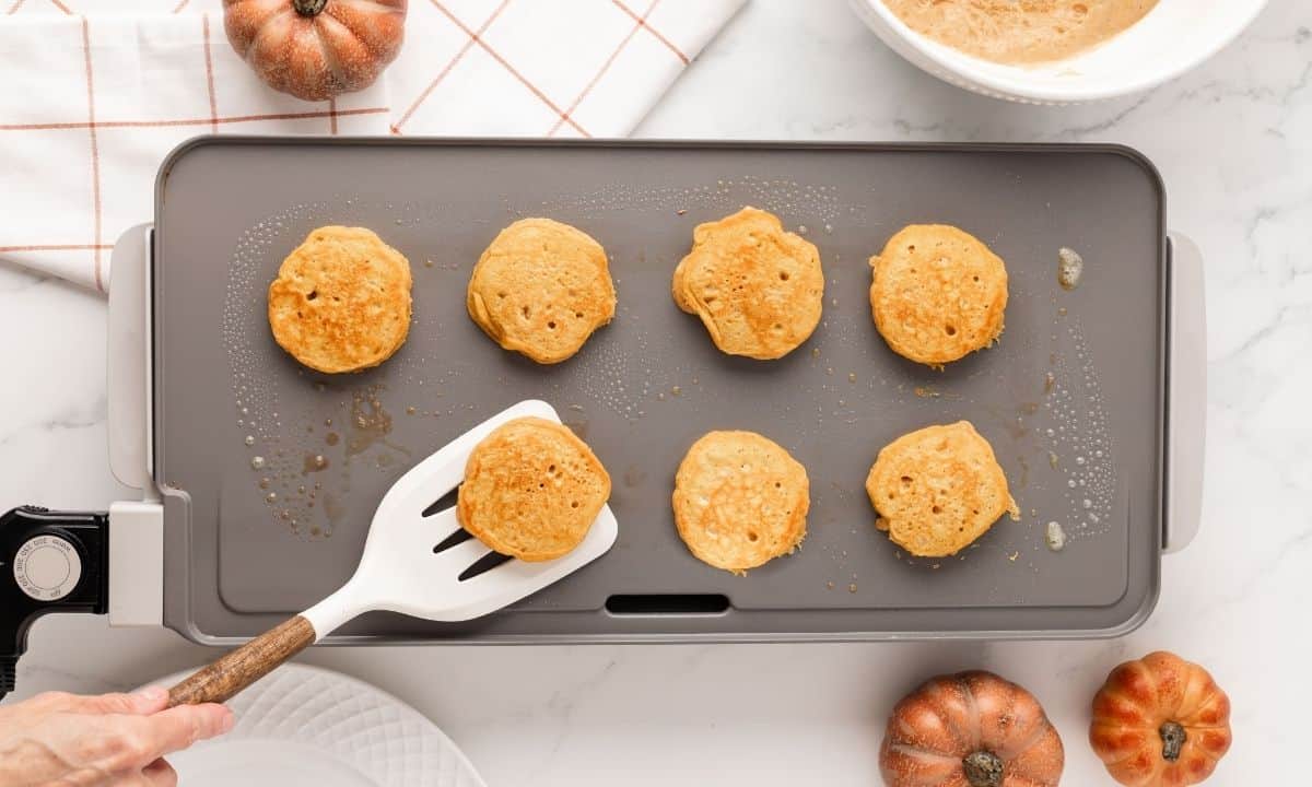 overhead view of cooking pumpkin pancakes on a griddle
