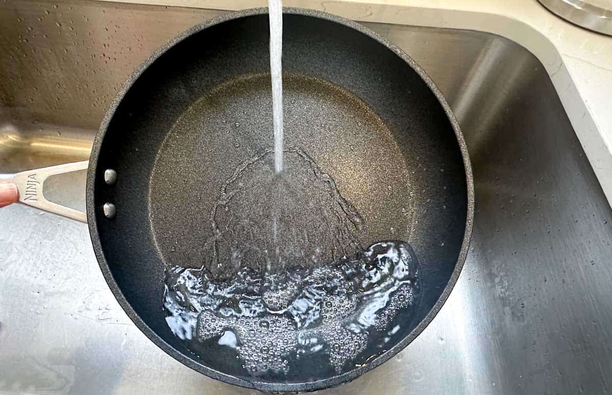 rinsing a hot pan under water to cool it down between pancake batches