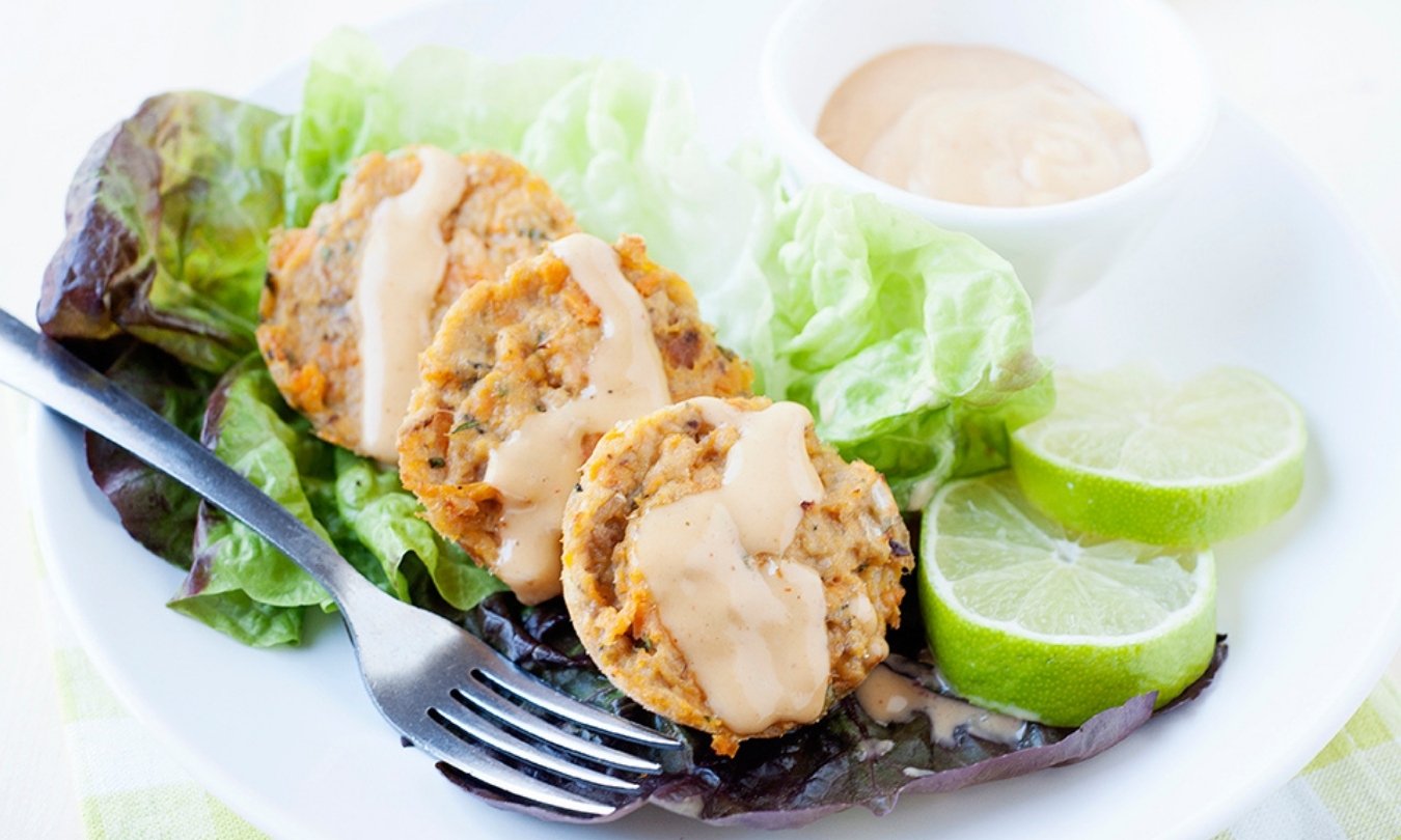 three salmon patties with lettuce, sauce and lime slices around
