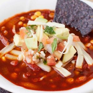 a bowl of healthy enchilada soup with tortilla chips in it