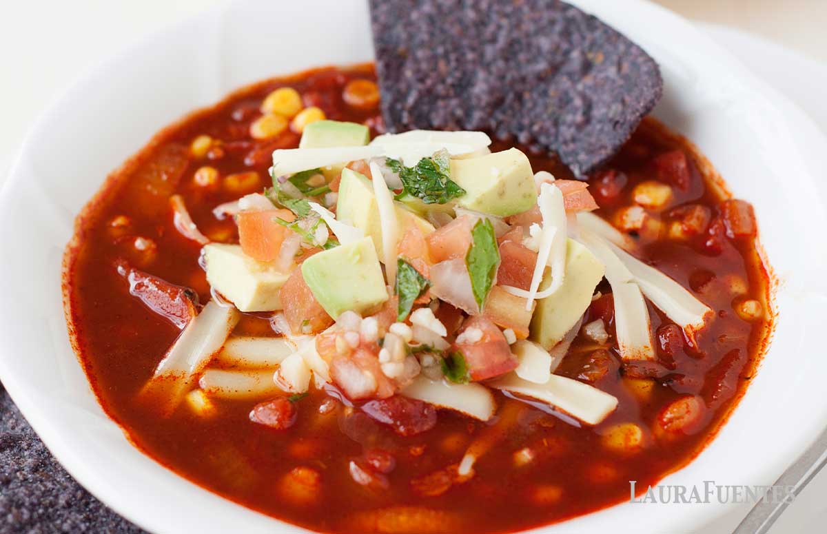 a bowl of healthy enchilada soup with tortilla chips in it