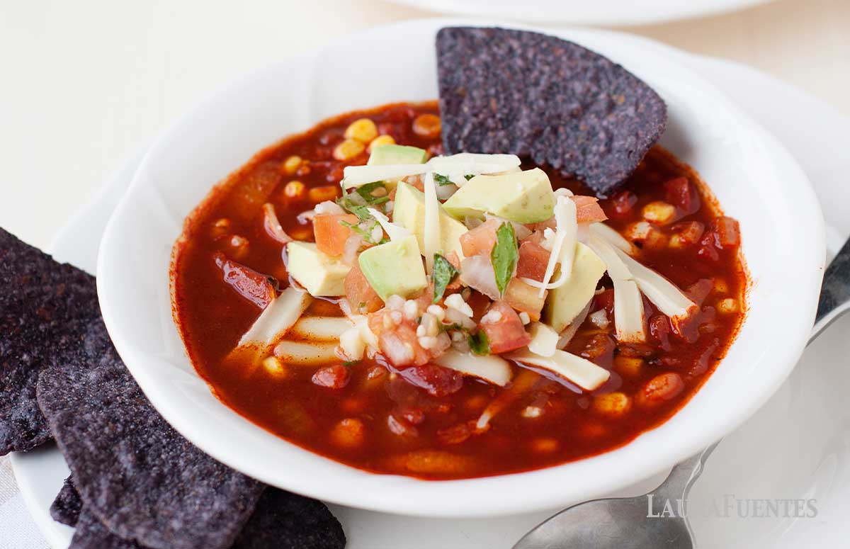 a bowl of healthy enchilada soup with tortilla chips in it