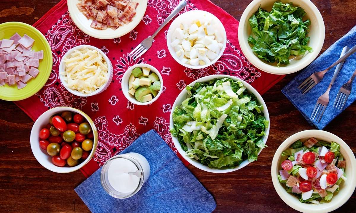 nine bowl with the ingredients for a cobb salad, plus a jar of ranch dressing