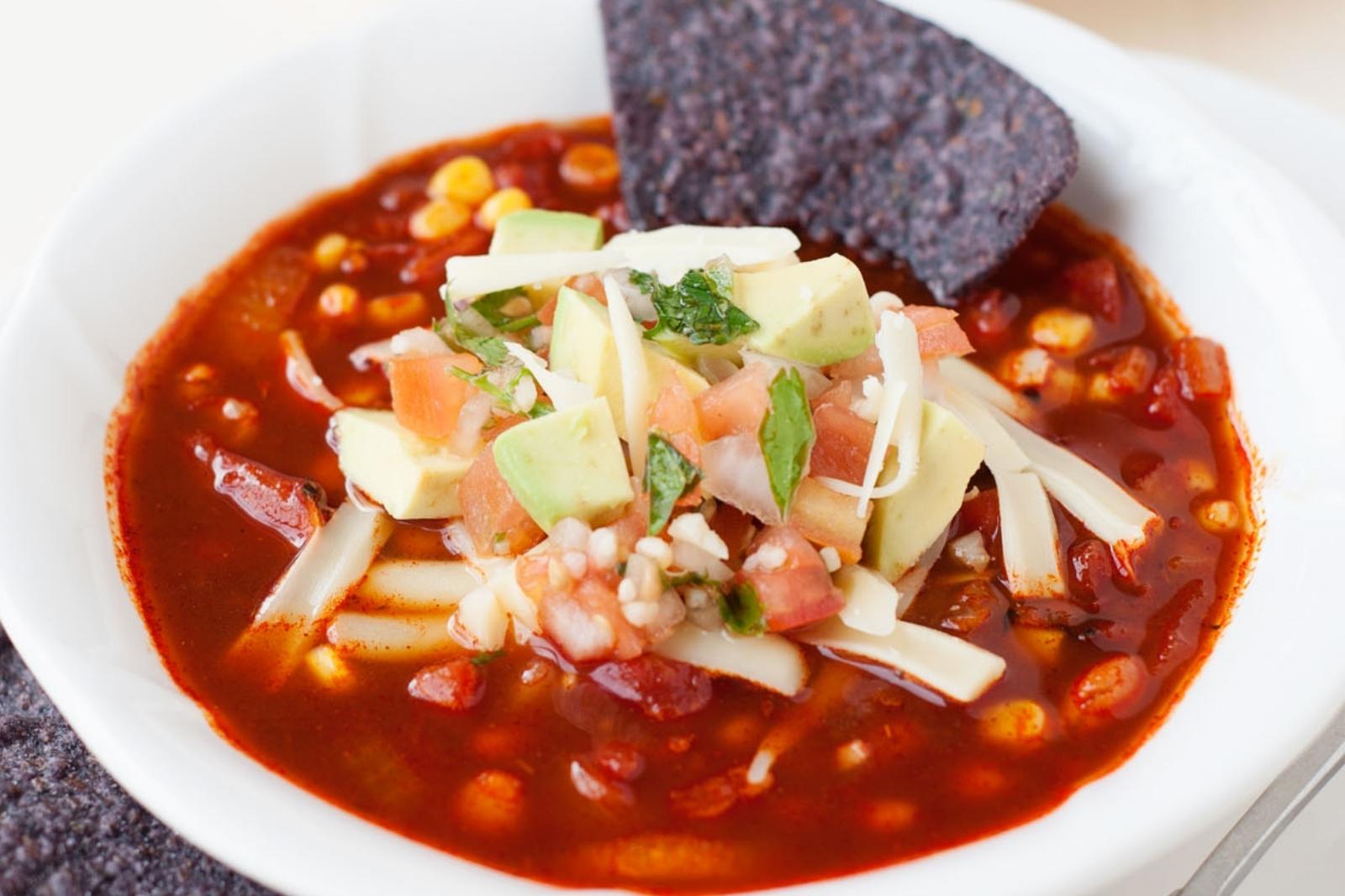 a bowl of healthy enchilada soup with tortilla chips in it