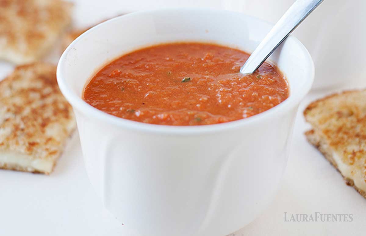 a small bowl of tomato soup with grilled cheese