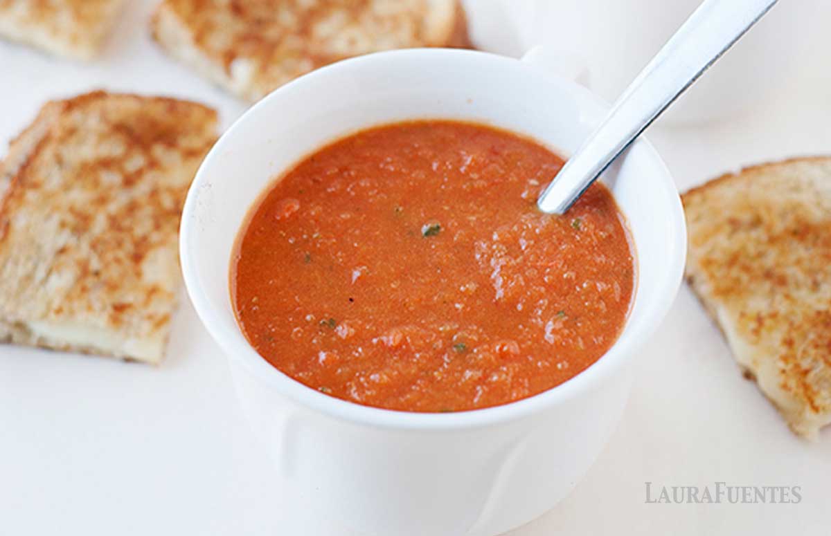 a small bowl of tomato soup with grilled cheese