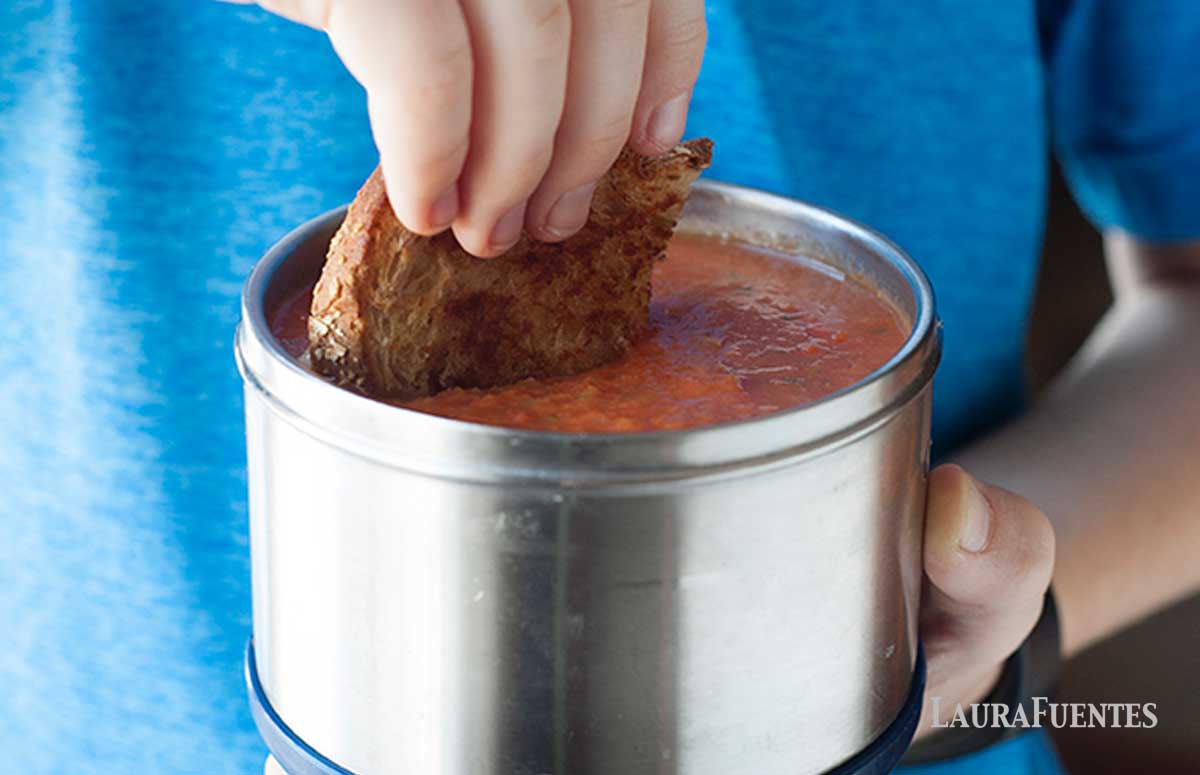 child dipping a slice of grilled cheese into small thermos of tomato soup