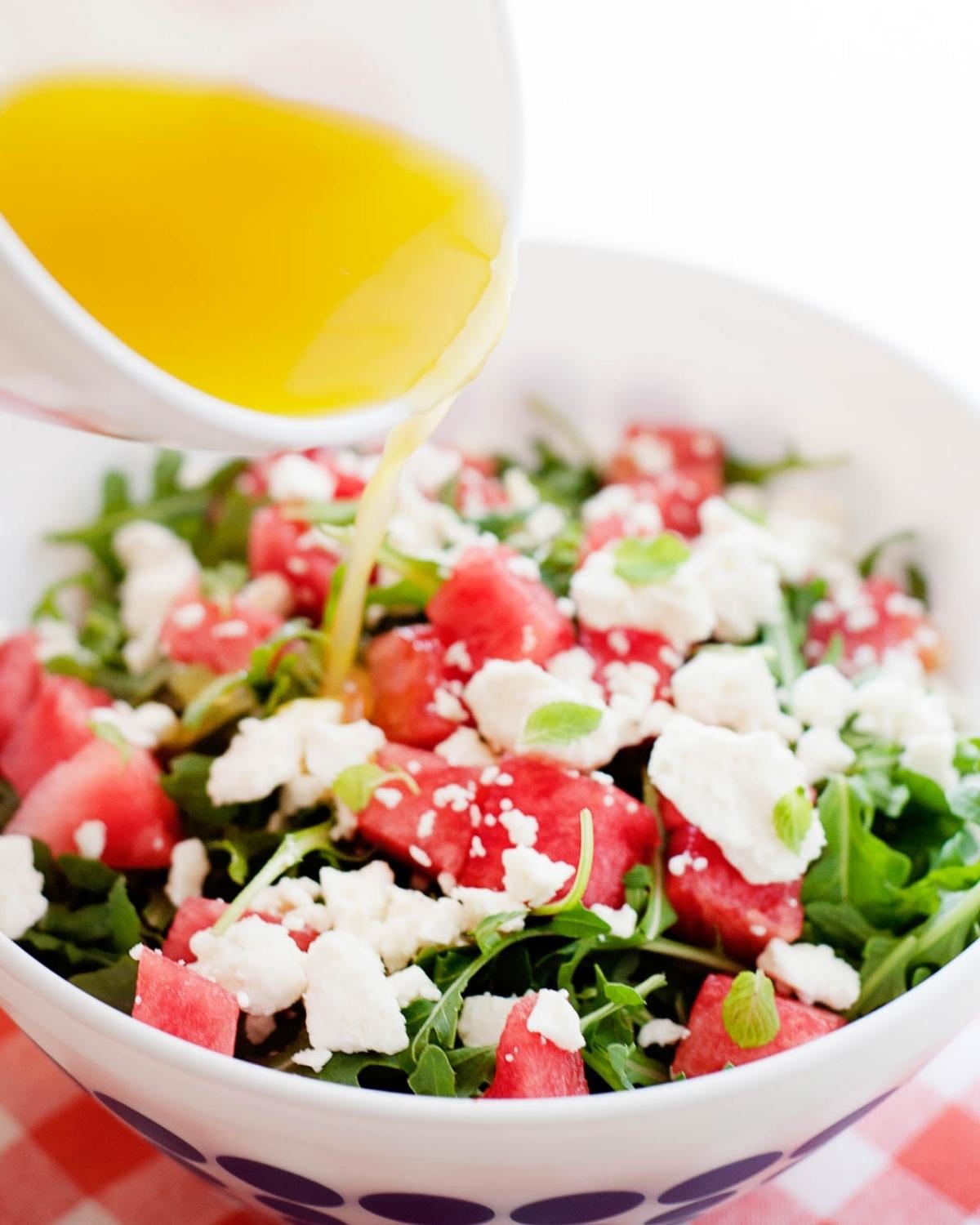 watermelon feta salad with orange dressing being poured over the top
