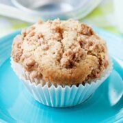 a single pear muffin with a cinnamon crumble topping on top of a blue plate