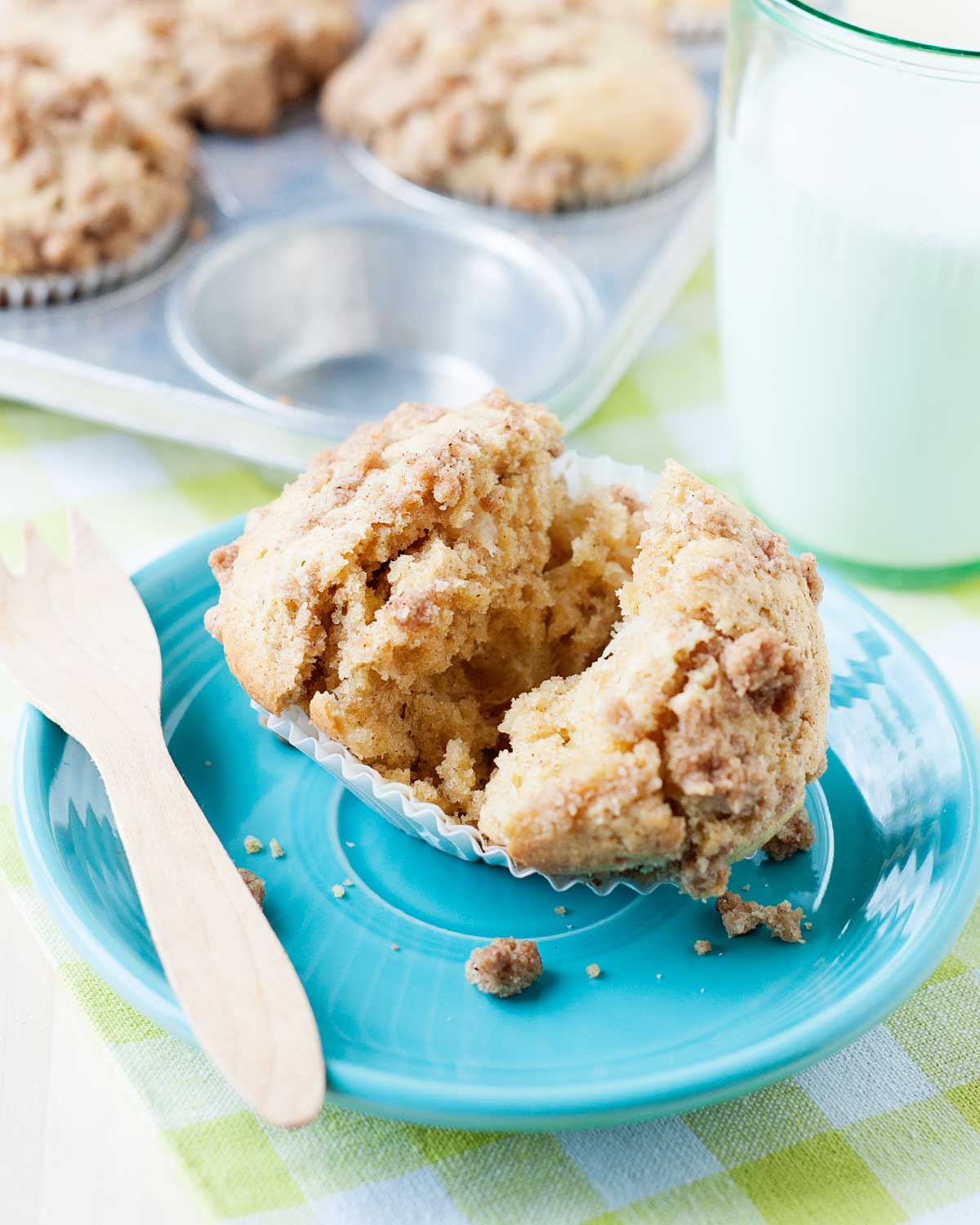 a single pear muffin with a cinnamon crumble topping opened in half to show the light texture on top of a blue plate