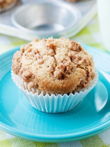 a single pear muffin with a cinnamon crumble topping on top of a blue plate