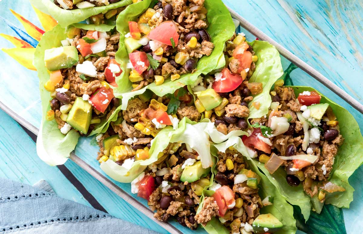 platte of taco lettuce cups topped with corn, tomatoes and avocado