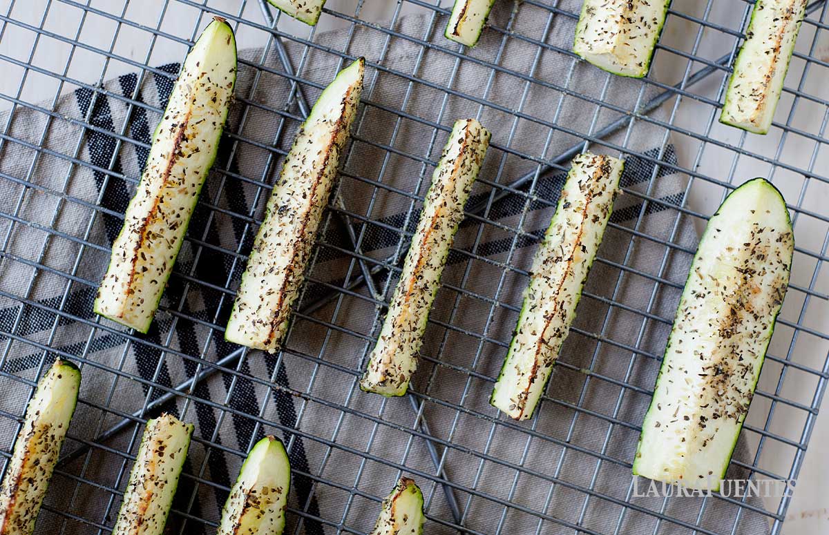 overhead view of seasoned, roasted zucchini spears in rows on a cooling rack. 