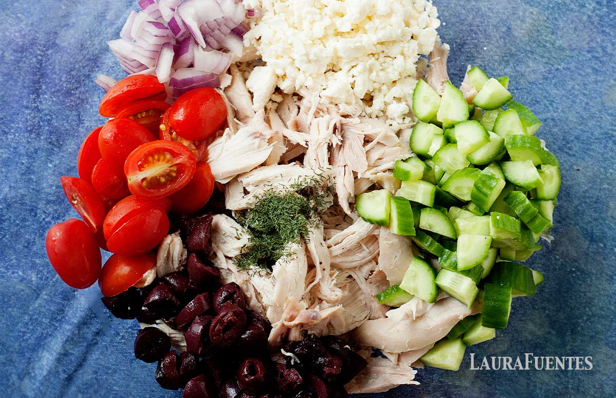 ingredients for greek chicken salad in a glass bowl 