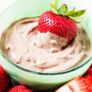 A small bowl with chocolate peanut butter yogurt dip an a strawberry inside