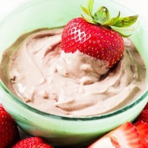 A small bowl with chocolate peanut butter yogurt dip an a strawberry inside