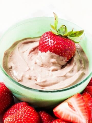 A small bowl with chocolate peanut butter yogurt dip an a strawberry inside