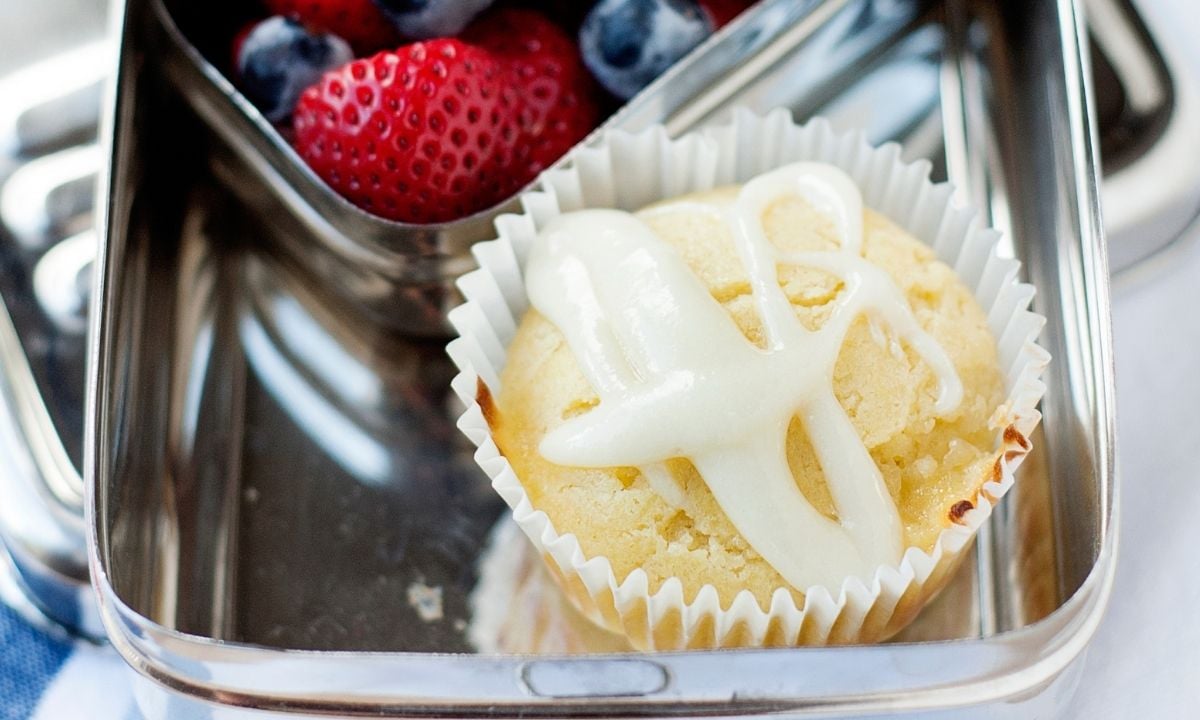a lunchbox with a lemon muffin and berries