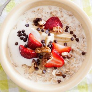 strawberry banana oatmeal topped with yogurt, nuts and chocolate chips