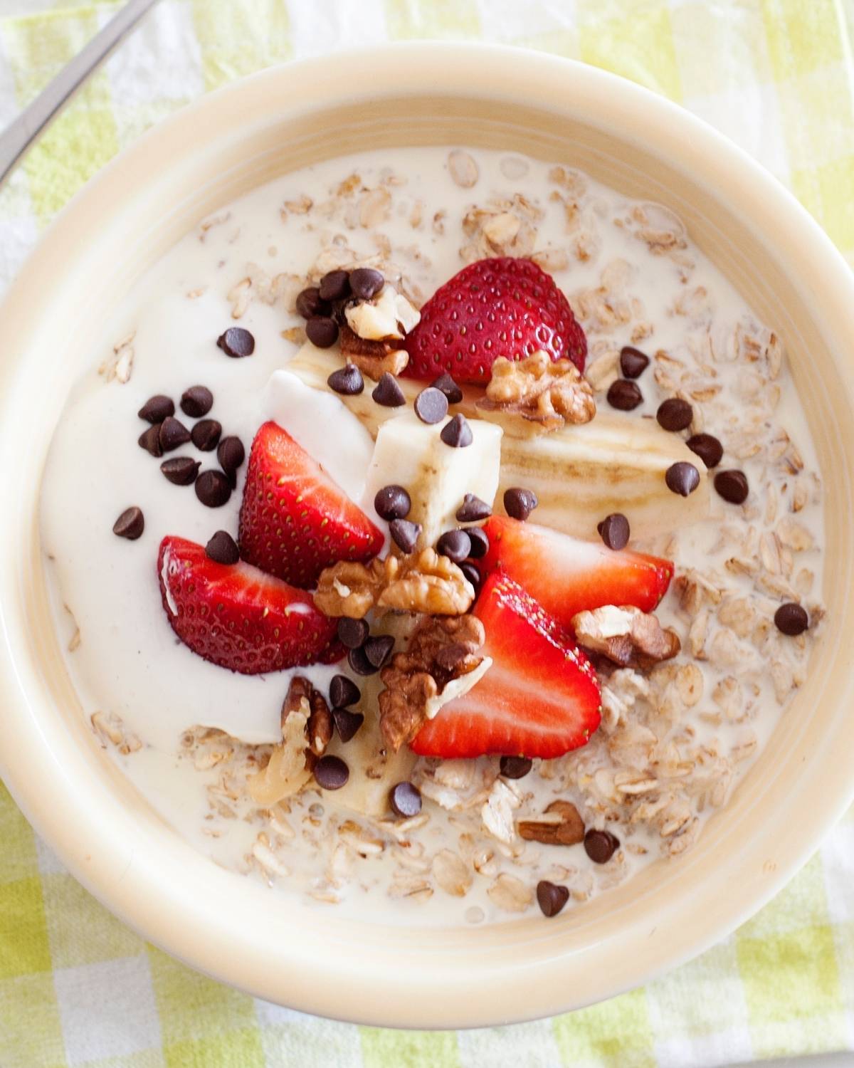 strawberry banana oatmeal topped with yogurt, nuts and chocolate chips