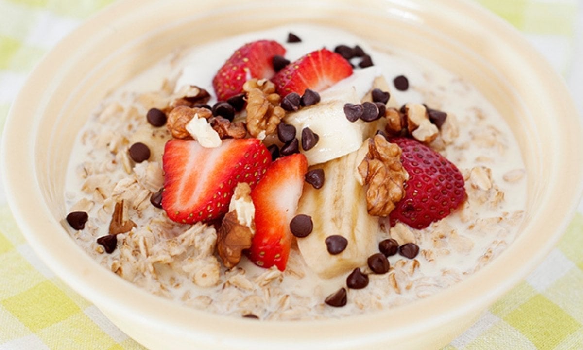 a bowl of oatmeal with banana, strawberry, walnuts and chocolate chips